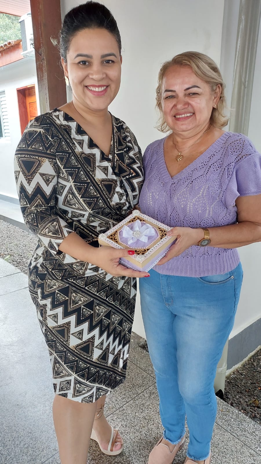 Secretária Adrianna Ramos recebendo um dos produtos do curso de embalagem das mãos da instrutora, Márcia Corrêa 